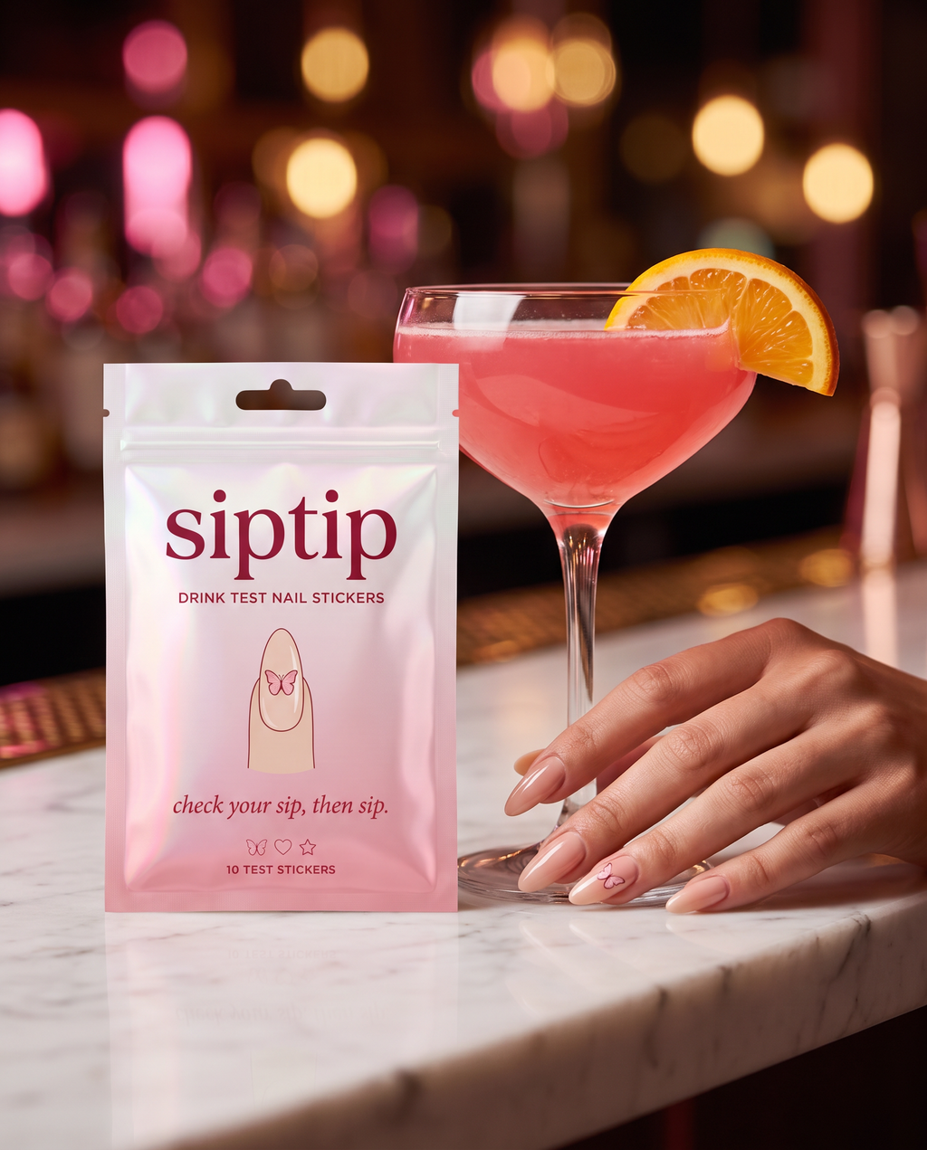 SipTip pouch on a marble bar next to a pink cocktail